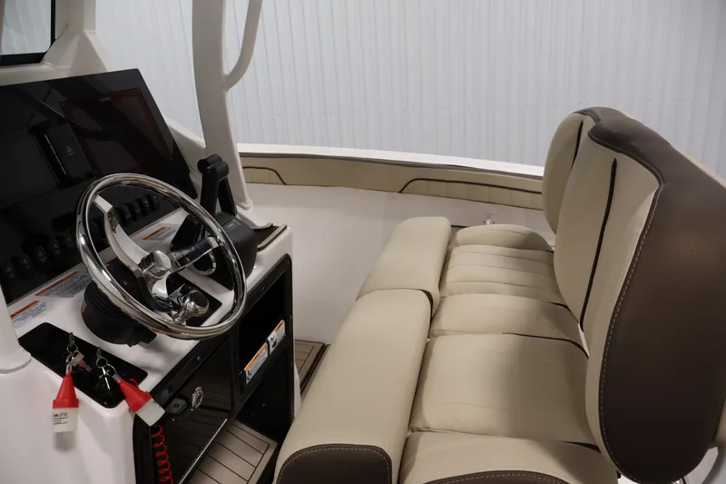 Slide: The Image of Interior of 2026 Yamaha Boats 252 FSH Sport, featuring steering wheel and beige seating. - 25