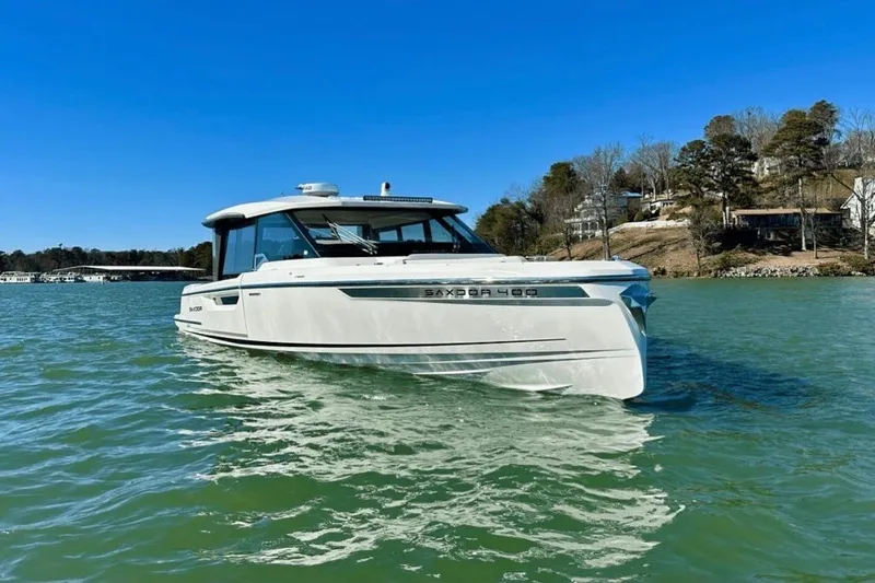 The Image of 2025 Saxdor 400 GTC boat cruising on a serene lake under a clear blue sky. - 1