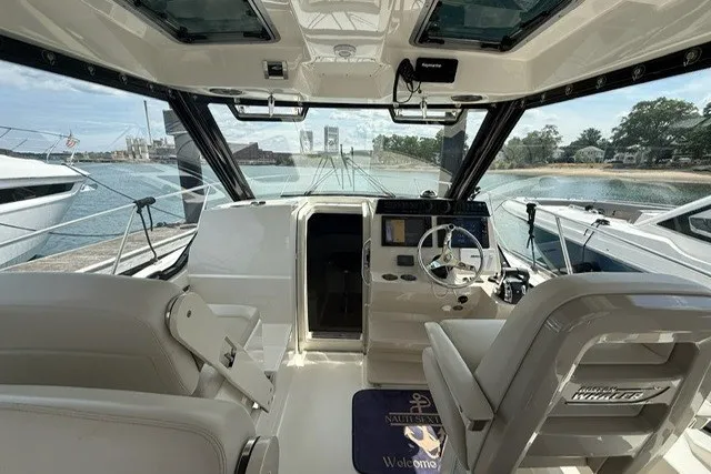 Slide: The Image of 2020 Boston Whaler 325 Conquest interior with helm, docked by the water. - 11