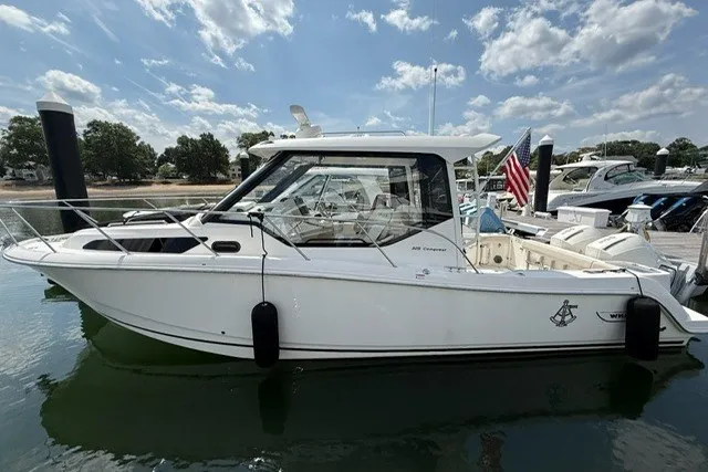 Slide: The Image of 2020 Boston Whaler 325 Conquest boat docked on calm water under a partly cloudy sky. - 1