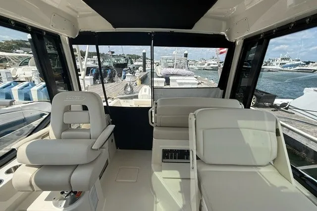 Slide: The Image of 2020 Boston Whaler 325 Conquest interior with plush seating, docked at marina. - 12