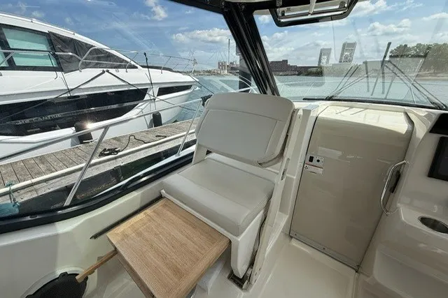Slide: The Image of 2020 Boston Whaler 325 Conquest interior with seating and table, docked by the water. - 14