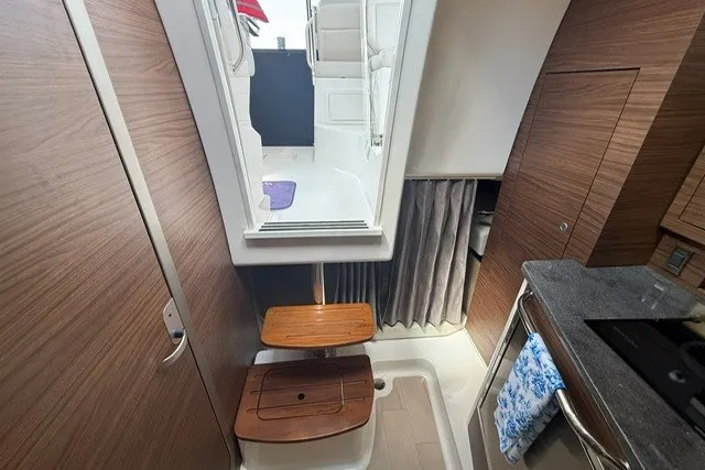 Slide: The Image of Interior of 2020 Boston Whaler 325 Conquest, featuring wooden steps and modern kitchen area. - 18