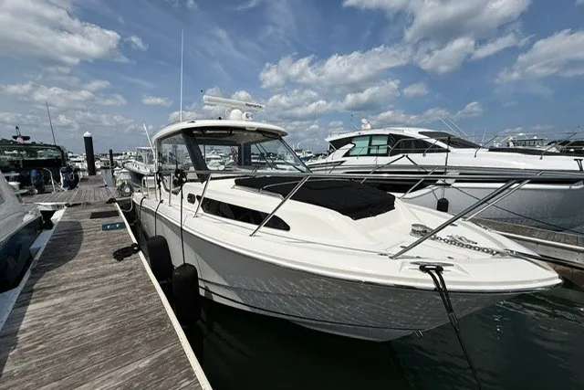 Slide: The Image of 2020 Boston Whaler 325 Conquest docked at marina under blue sky. - 2