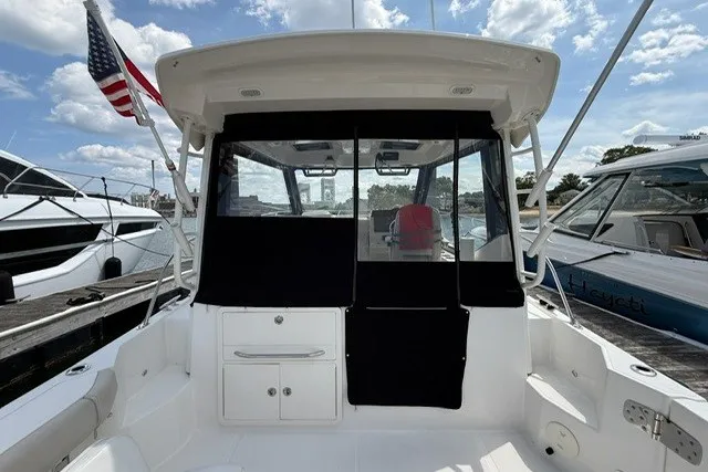 Slide: The Image of 2020 Boston Whaler 325 Conquest boat docked, featuring a spacious cockpit and American flag. - 10