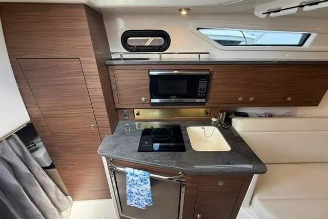 Slide: The Image of Interior of 2020 Boston Whaler 325 Conquest, featuring a modern kitchenette with wood cabinetry. - 22