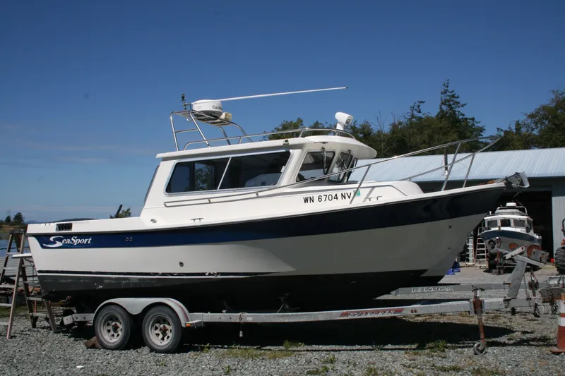 The Image of 2007 Sea Sport 2200 Sportsman boat on trailer, parked outdoors under clear blue sky. - 0