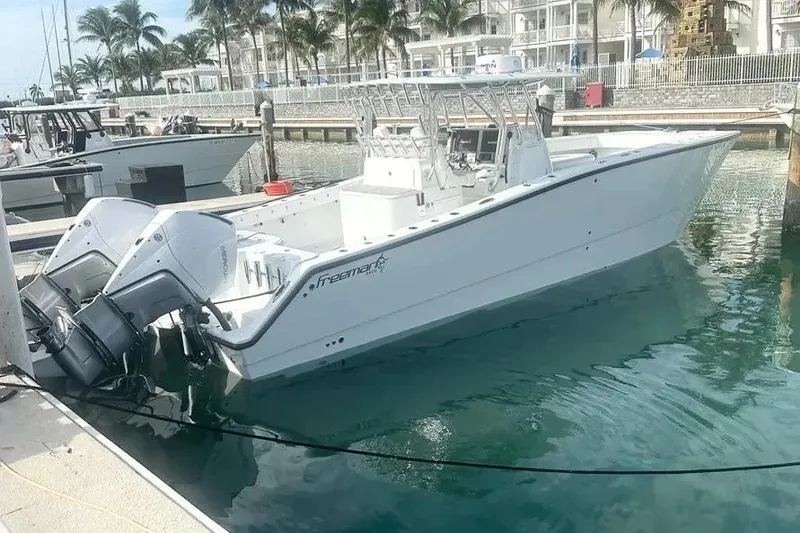 Slide: The Image of 2022 Freeman 34VH boat docked in marina, featuring dual outboard engines. - 13
