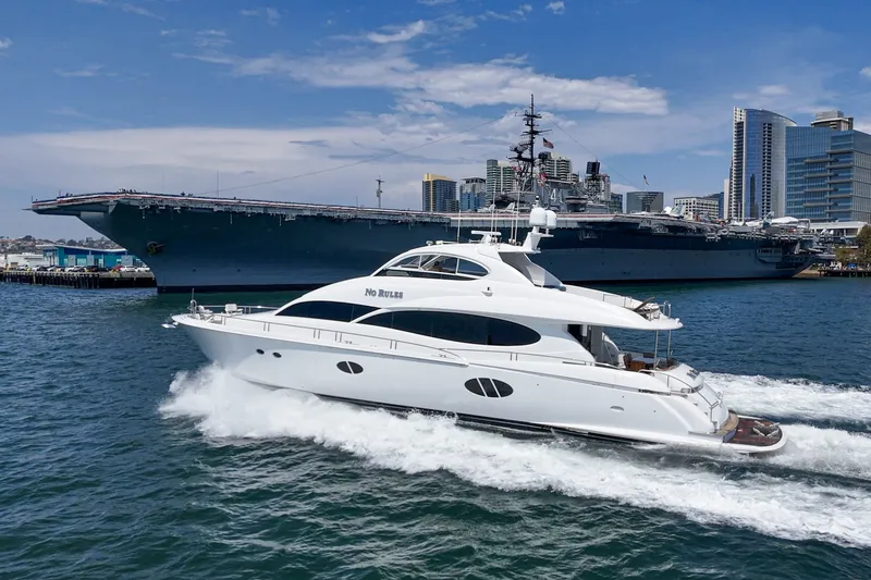 Slide: The Image of 2006 Lazzara 84 Flybridge yacht cruising near a large battleship in a bustling harbor. - 0