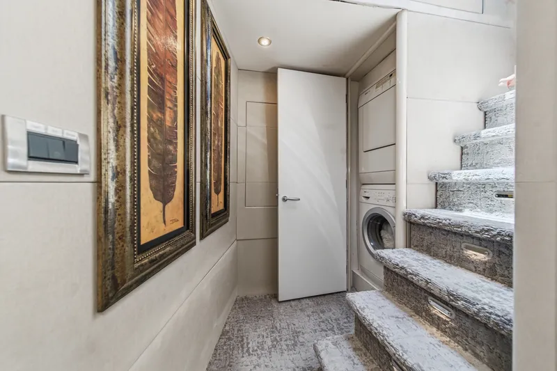 Slide: The Image of Laundry area with stacked washer-dryer and art on a 2006 Lazzara 84 Flybridge yacht. - 63