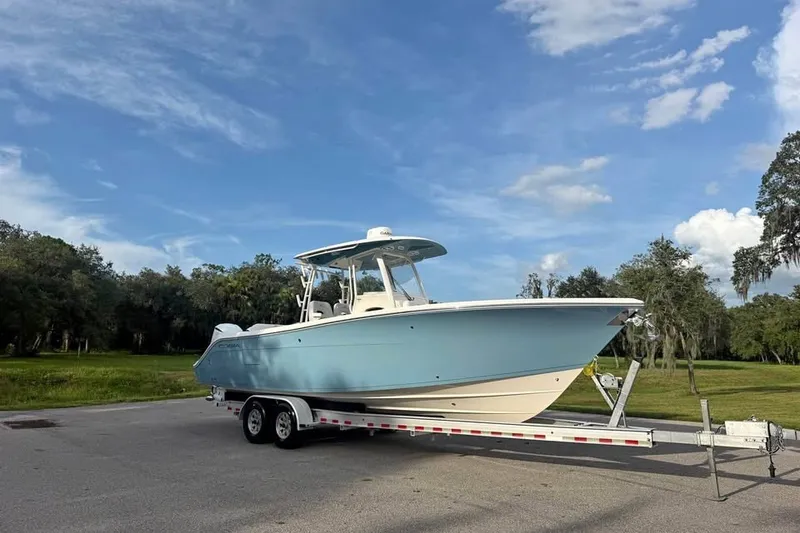 The Image of 2020 Cobia 301 Center Console boat on trailer under blue sky. - 0