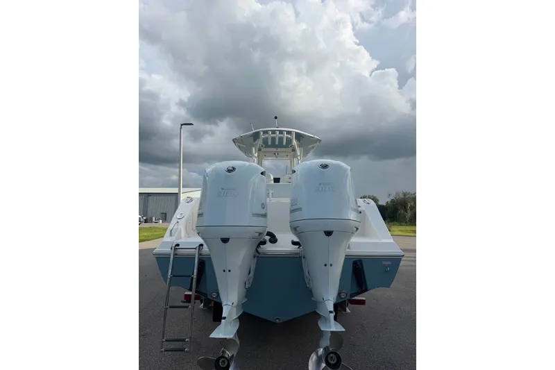Slide: The Image of 2020 Cobia 301 Center Console boat with twin outboard engines under cloudy sky. - 18
