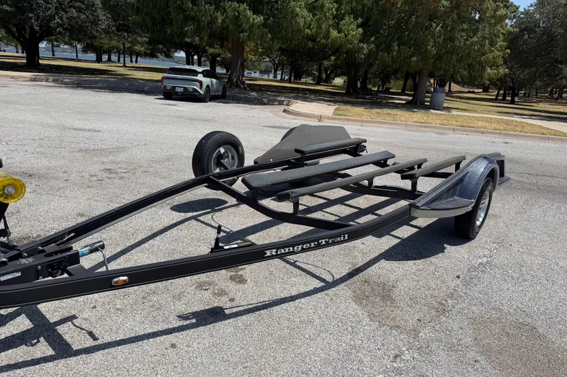 Slide: The Image of 2020 Ranger Z518 boat trailer parked in a sunny, tree-lined area. - 58