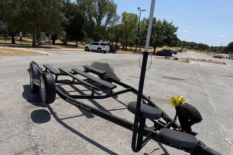 Slide: The Image of 2020 Ranger Z518 boat trailer in a sunny parking lot with trees in the background. - 57