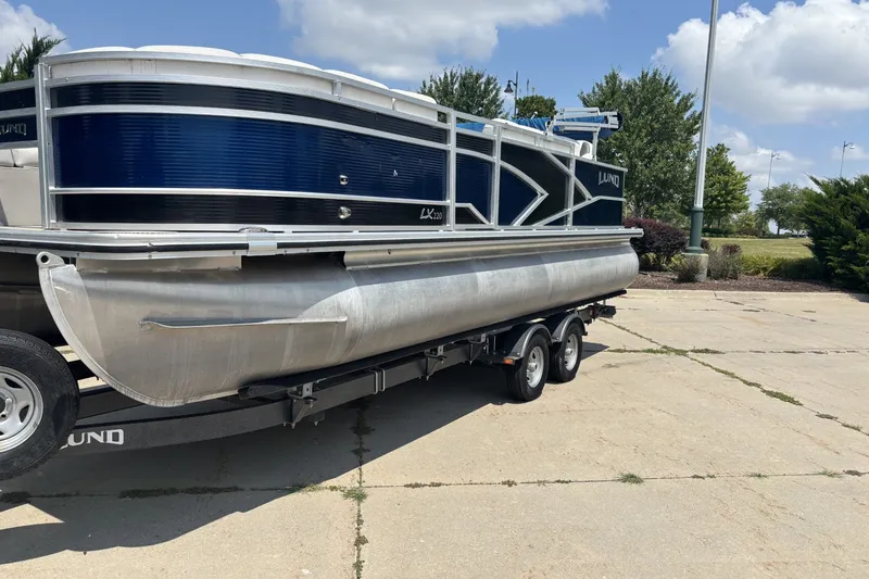 Slide: The Image of 2020 Lund LX220 Pontoon boat on trailer, parked outdoors under a clear sky. - 3