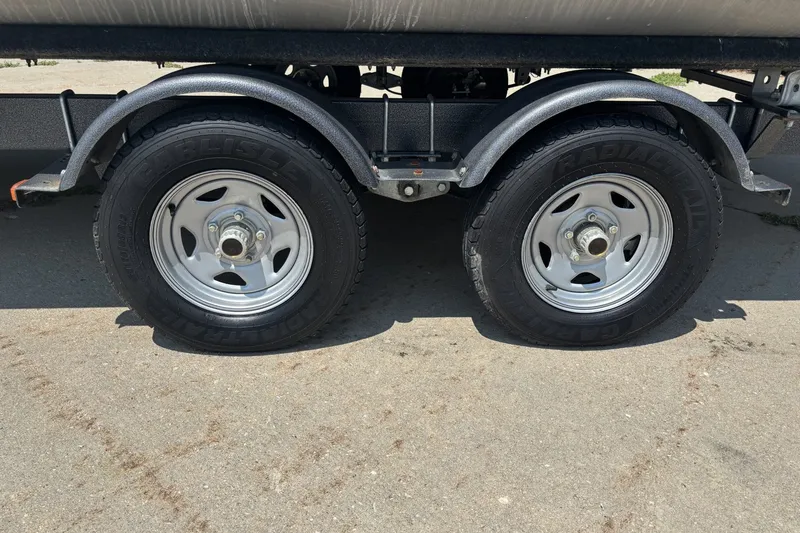 Slide: The Image of Trailer wheels of a 2020 Lund LX220 Pontoon on concrete pavement. - 17