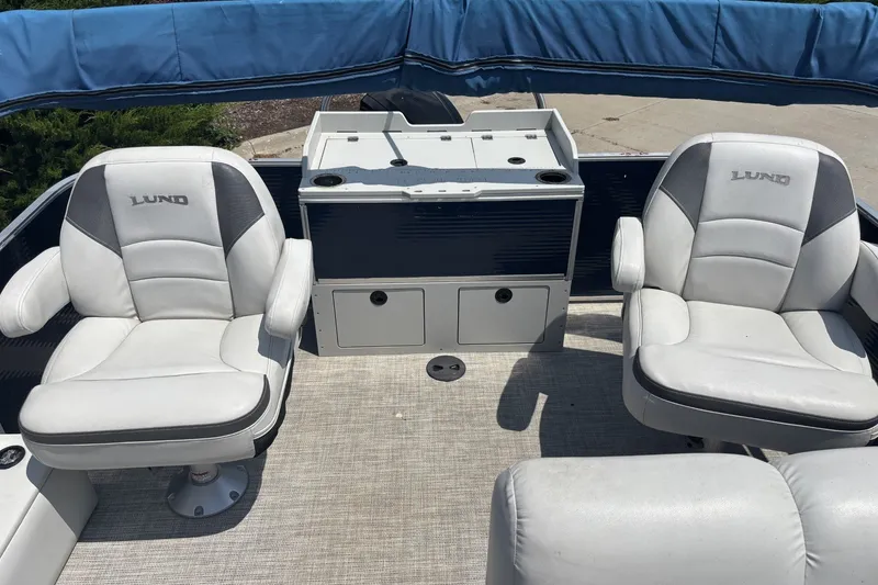 Slide: The Image of 2020 Lund LX220 Pontoon interior with two white cushioned seats and storage unit. - 12