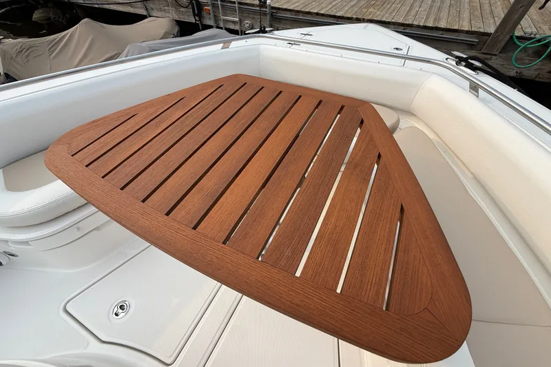 Slide: The Image of Teak table on 2016 Boston Whaler 420 Outrage boat, docked with white seating. - 17