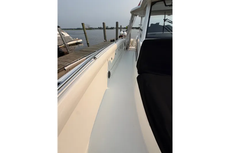 Slide: The Image of 2016 Boston Whaler 420 Outrage boat docked, showcasing sleek deck design and seating area. - 45