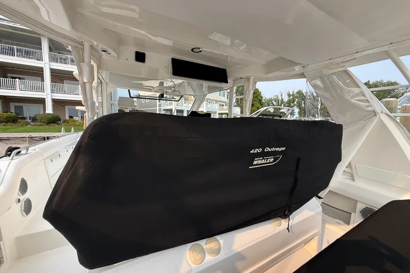 Slide: The Image of 2016 Boston Whaler 420 Outrage boat interior with covered console, docked near buildings. - 53