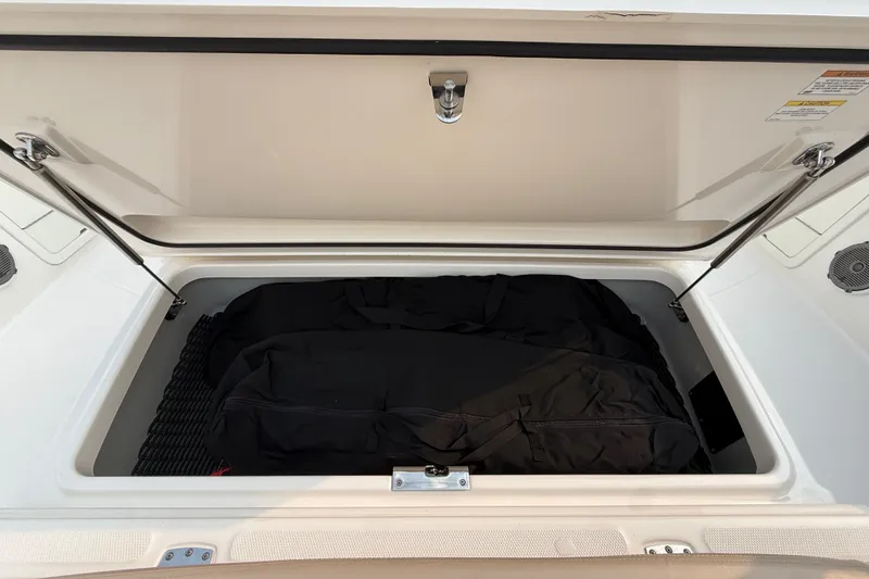 Slide: The Image of Open storage compartment on 2016 Boston Whaler 420 Outrage boat, containing black bags. - 21