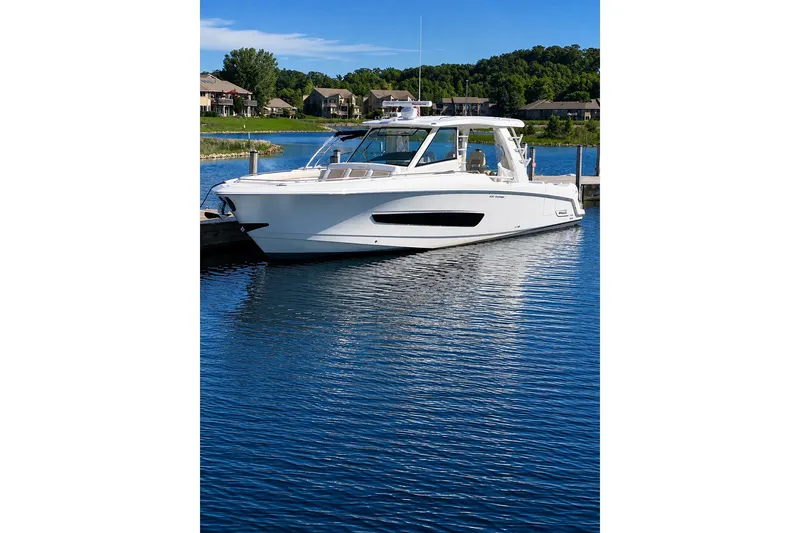 Slide: The Image of 2016 Boston Whaler 420 Outrage boat docked on a serene lake. - 4