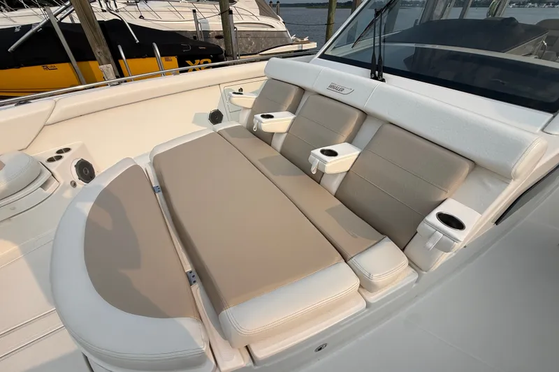 Slide: The Image of Luxurious seating on a 2016 Boston Whaler 420 Outrage boat, featuring cup holders and beige cushions. - 22