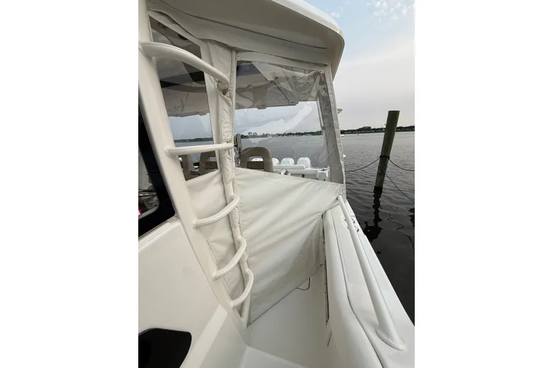 Slide: The Image of 2016 Boston Whaler 420 Outrage boat docked, featuring sleek white exterior and protective canopy. - 12