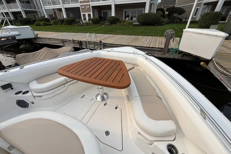 Slide: The Image of 2016 Boston Whaler 420 Outrage boat with cushioned seating and wooden table at dock. - 18