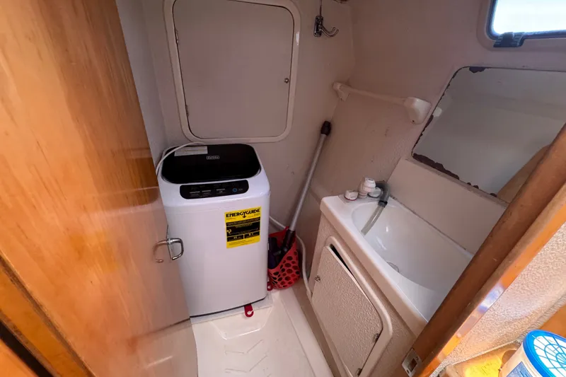 Slide: The Image of Small bathroom with washing machine, sink, and mirror on a 2000 St Francis 44 boat. - 28