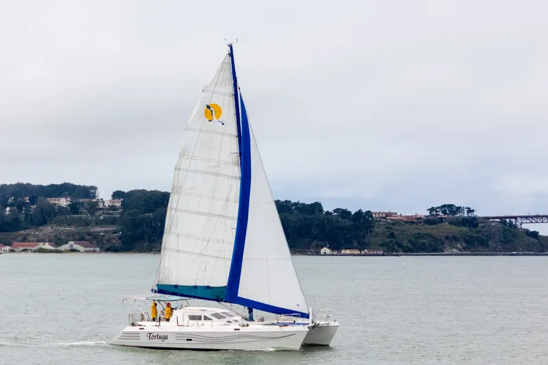 Slide: The Image of Sailing catamaran St Francis 44, 2000 model, cruising near a scenic coastline. - 2