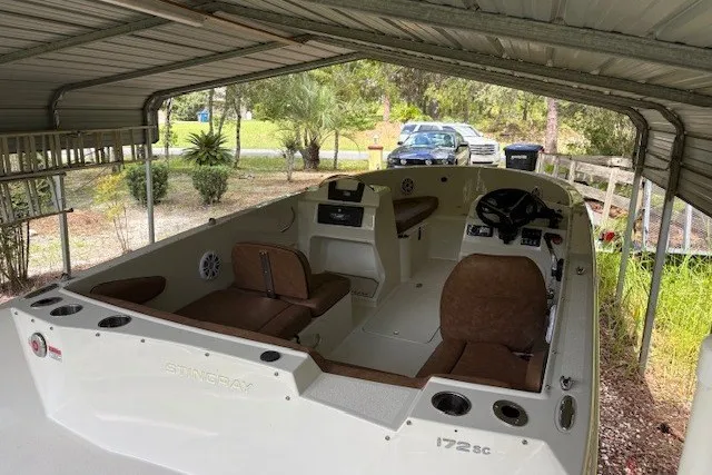 Slide: The Image of 2021 Stingray 172 SC boat under a metal canopy, featuring brown seating and a steering console. - 21