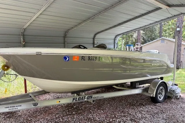 The Image of 2021 Stingray 172 SC boat on trailer under metal canopy. - 0