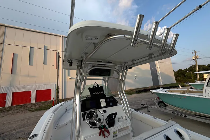 Slide: The Image of 2013 Robalo R260 Center Console boat with T-top and rod holders, parked outdoors. - 32