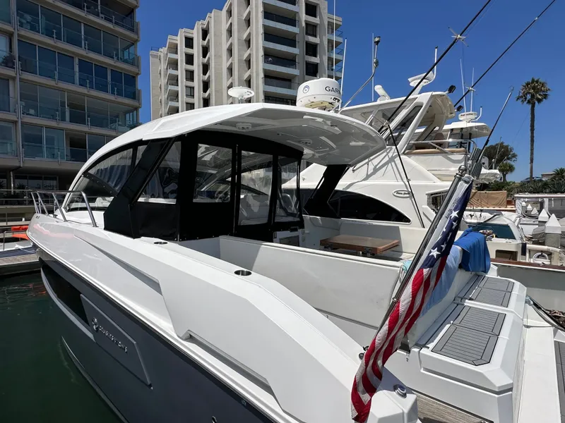 Slide: The Image of A 2018 Cruisers Yachts 390 Express Coupe docked at a marina. Modern buildings in the background. - 4
