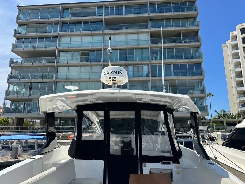 Slide: The Image of A 2018 Cruisers Yachts 390 Express Coupe docked in front of a modern building at the marina. - 46