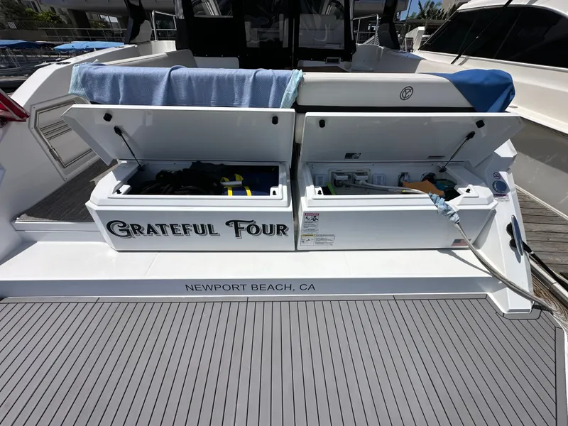 Slide: The Image of The image shows the stern of a 2018 Cruisers Yachts 390 Express Coupe. There are two open storage compartments labeled "Grateful Four" with a reference to Newport Beach, CA. - 8