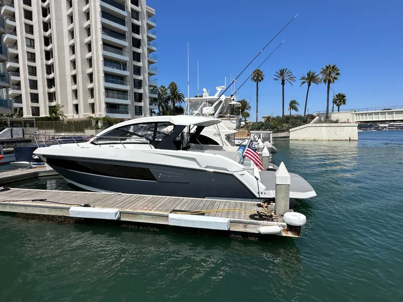 Slide: The Image of A 2018 Cruisers Yachts 390 Express Coupe docked near a modern building. - 49