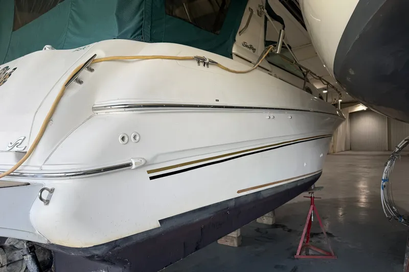 Slide: The Image of 1998 Sea Ray 290 Sundancer boat in storage, side view with green cover. - 3