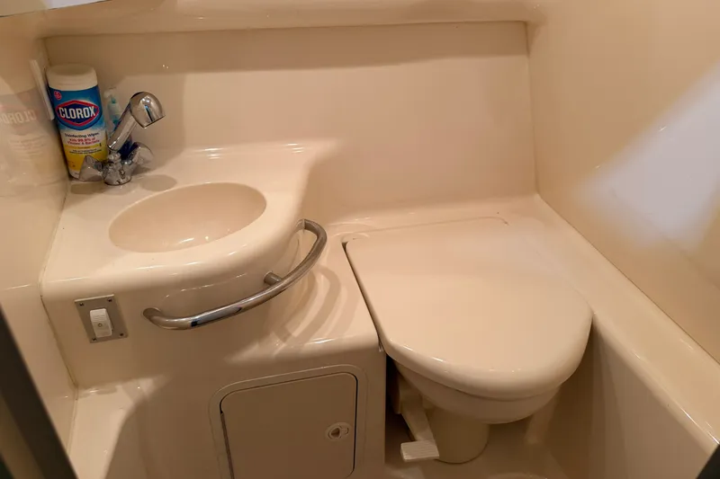 Slide: The Image of Compact bathroom in a 1998 Sea Ray 290 Sundancer boat, featuring a sink and toilet. - 21