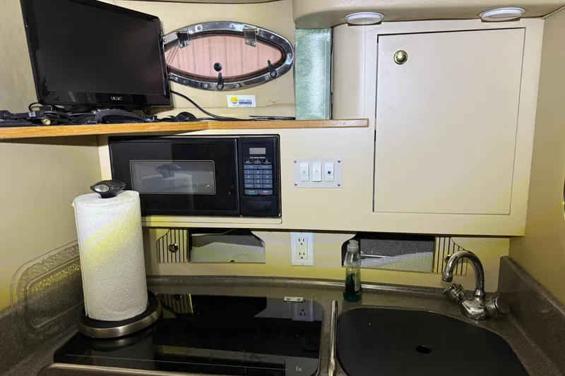 Slide: The Image of 1998 Sea Ray 290 Sundancer cabin kitchen with microwave, sink, and TV. - 17