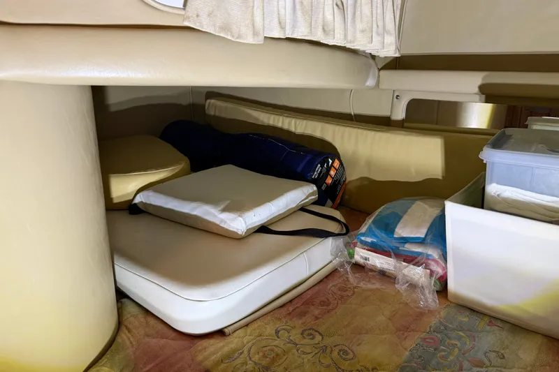 Slide: The Image of Interior storage area of a 1998 Sea Ray 290 Sundancer boat with cushions and supplies. - 23