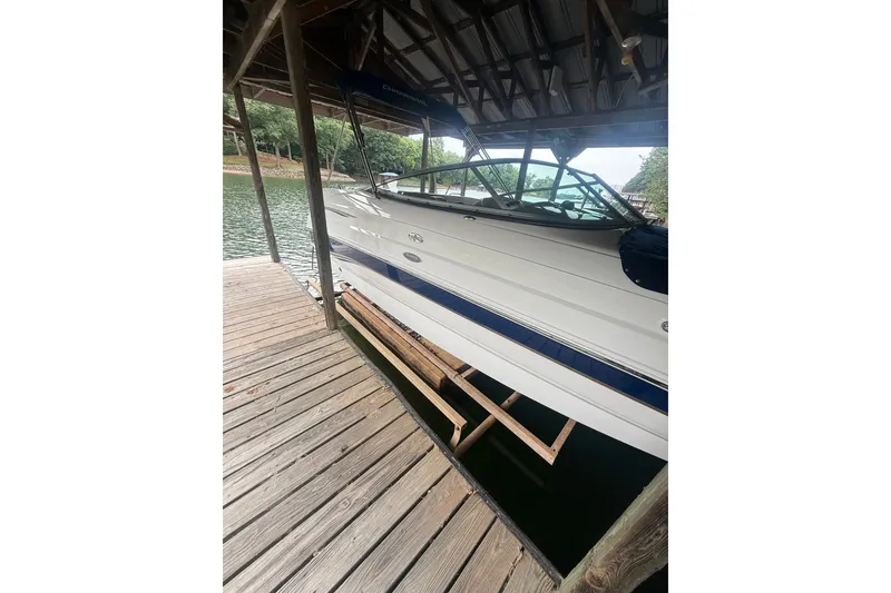The Image of 2005 Chaparral Sunesta 216 boat docked under a wooden shelter by the water. - 4