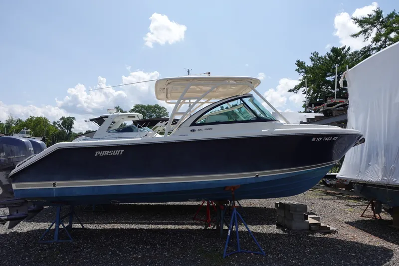 The Image of 2015 Pursuit DC 265 Dual Console boat on stands, outdoors under a blue sky. - 0