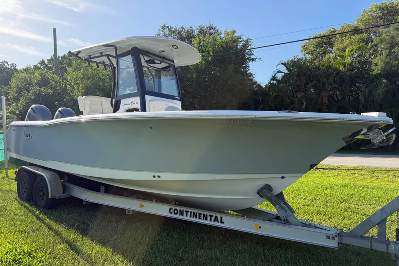 The Image of 2023 Sea Hunt Gamefish 25 boat on trailer, parked on grass, sunny day. - 0