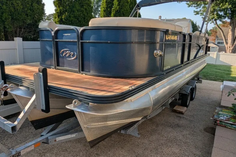 Slide: The Image of 2017 Manitou 23 Aurora VP pontoon boat on trailer, parked outdoors. - 24