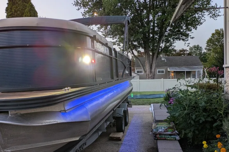 Slide: The Image of 2017 Manitou 23 Aurora VP pontoon boat with blue LED lights on a trailer. - 14