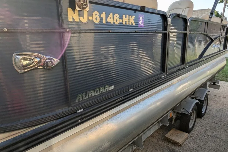 Slide: The Image of 2017 Manitou 23 Aurora VP pontoon boat on trailer, side view with registration number. - 23