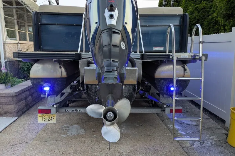 Slide: The Image of Rear view of a 2017 Manitou 23 Aurora VP boat on a trailer with blue lights. - 12