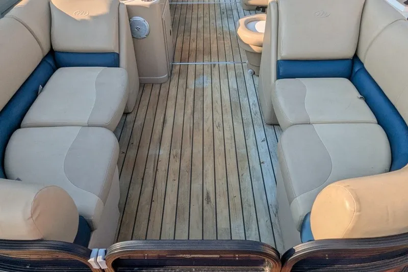 Slide: The Image of 2017 Manitou 23 Aurora VP boat interior with beige and blue seating, wooden deck. - 8